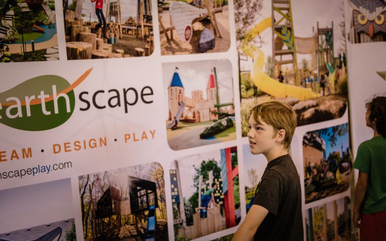 visitors admire photographs of completed Earthscape playgrounds new design studio